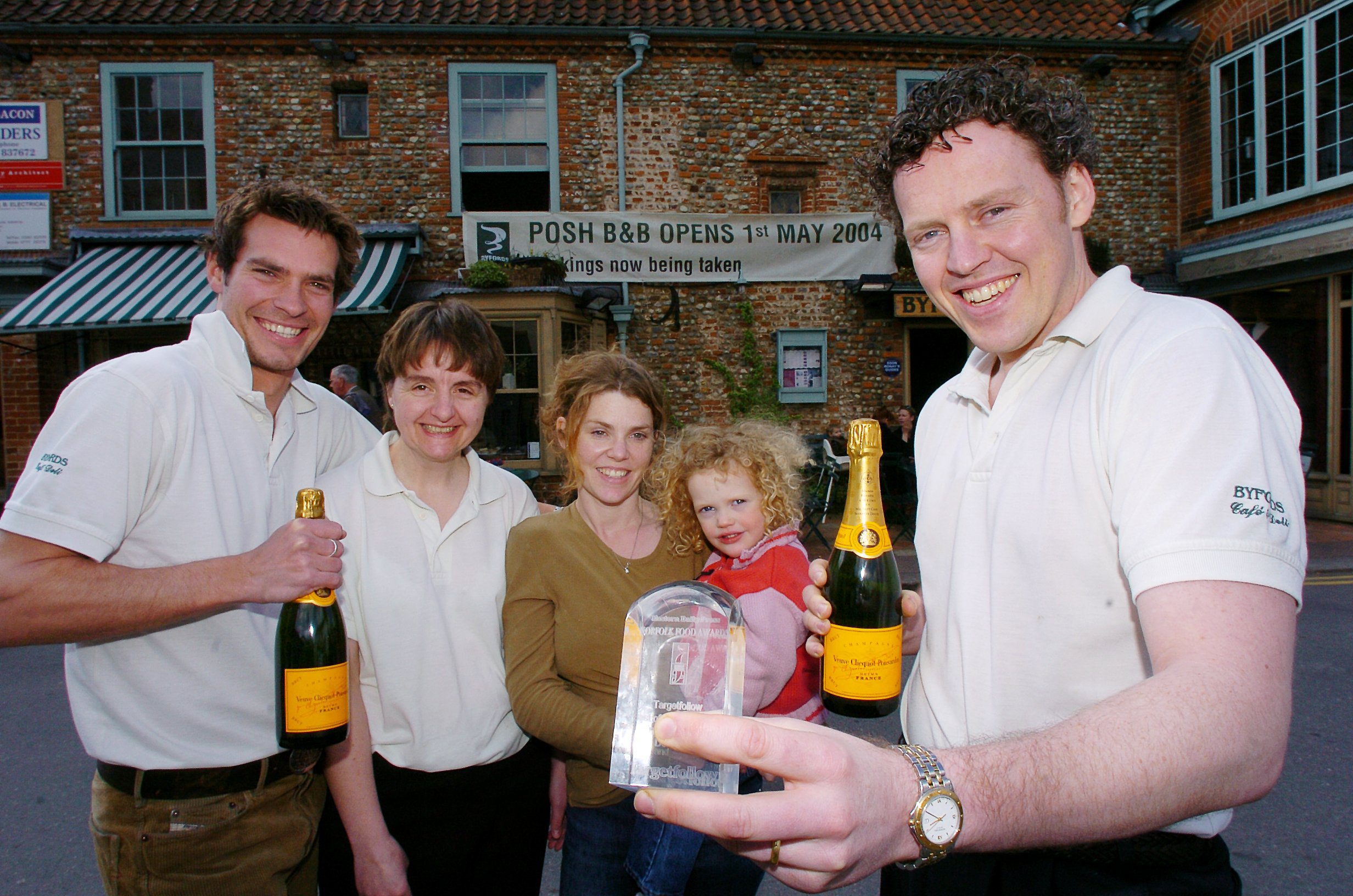 The Wilson Family stood outside Byfords with a banner up that says 'POSH B&B OPENS 1ST MAY 2004'